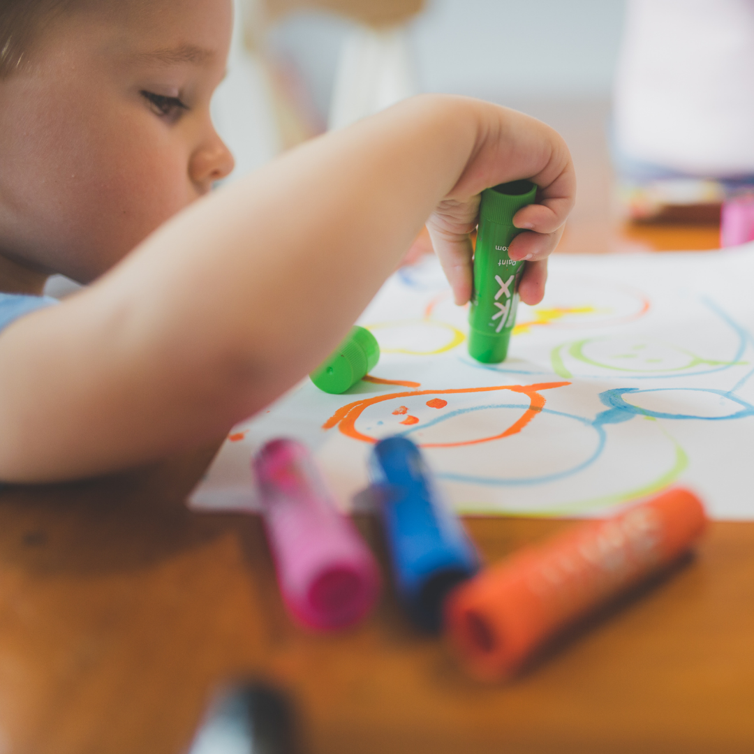 Child coloring on a page with markers
